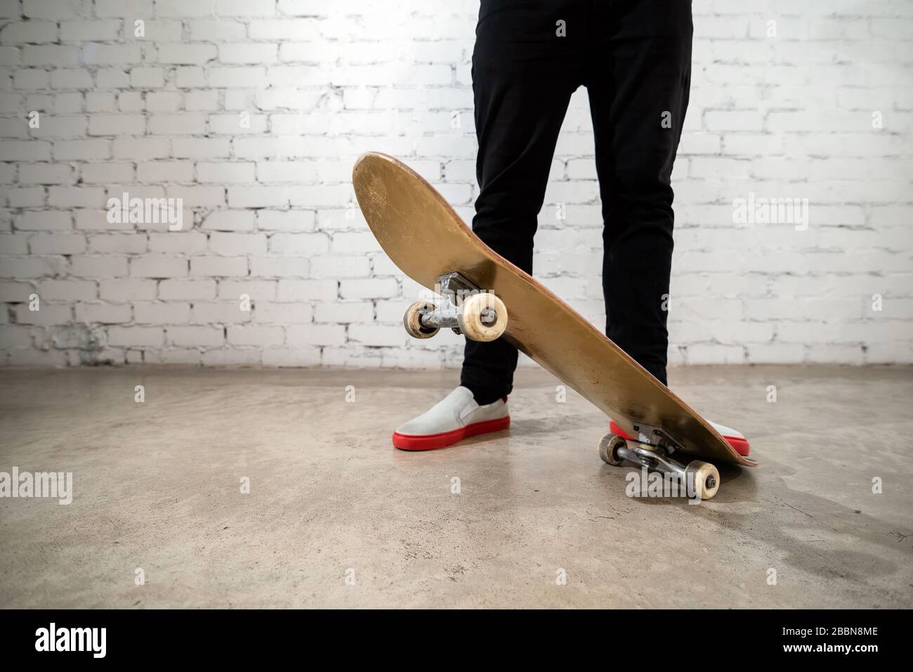 Close up of skateboarder standing next to a white brick wall. Athletic  teenager wearing jeans with a skateboard. Urban style, youth culture Stock  Photo - Alamy