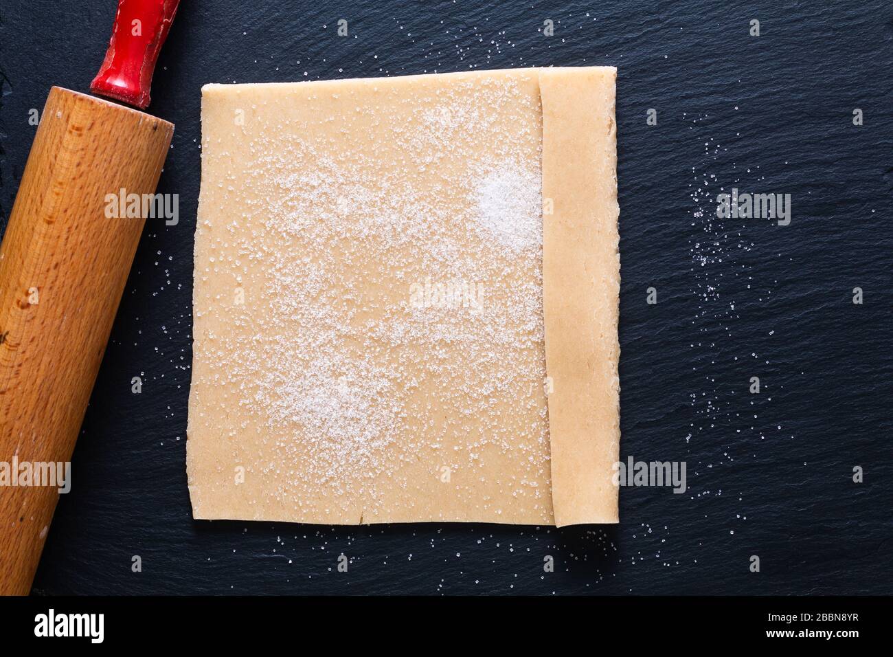 Food concept Homemade raw organic Puff Pastry dough for baked pie, cookies or tarts on black slate board Stock Photo