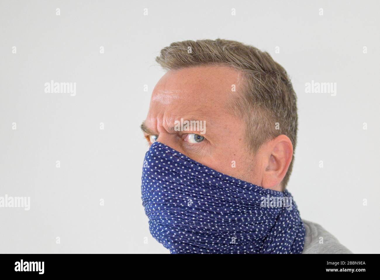 Paranoid man wearing a face guard against Covid-19 or coronavirus during the pandemic looking around with fear in a head portrait on white with copy s Stock Photo