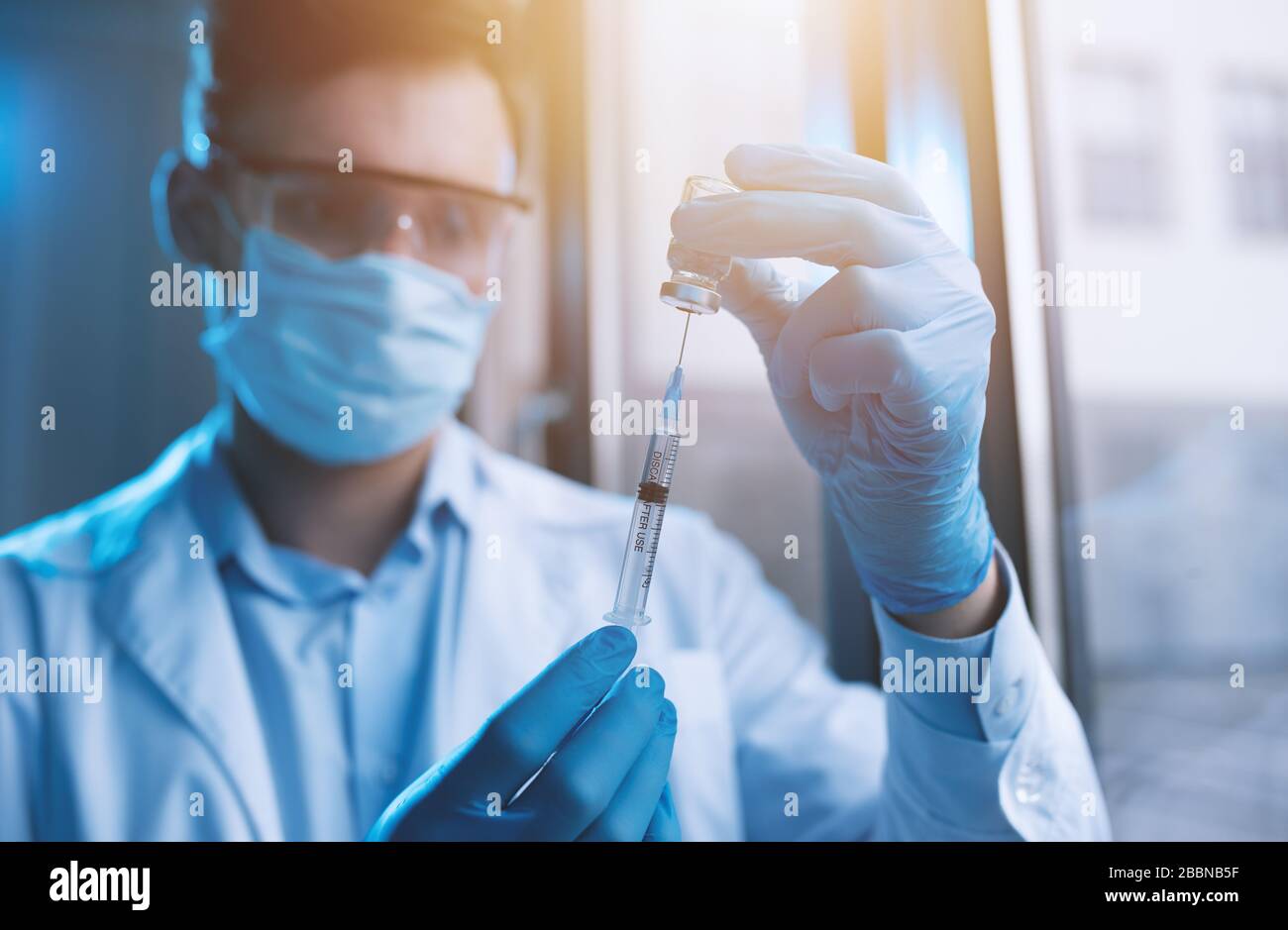 Medic with mask works on a solution for covid 19 virus. Concept of medical research Stock Photo