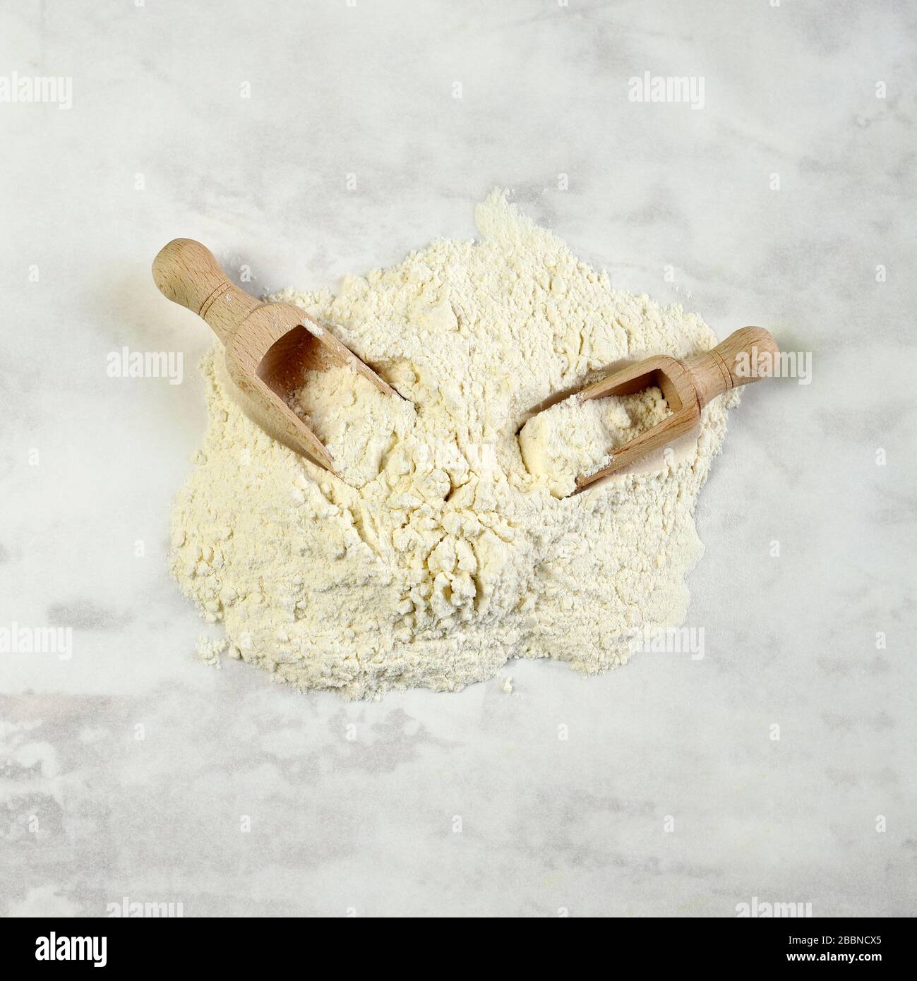 Wheat flour with two wooden scoops isolated on white background. Top