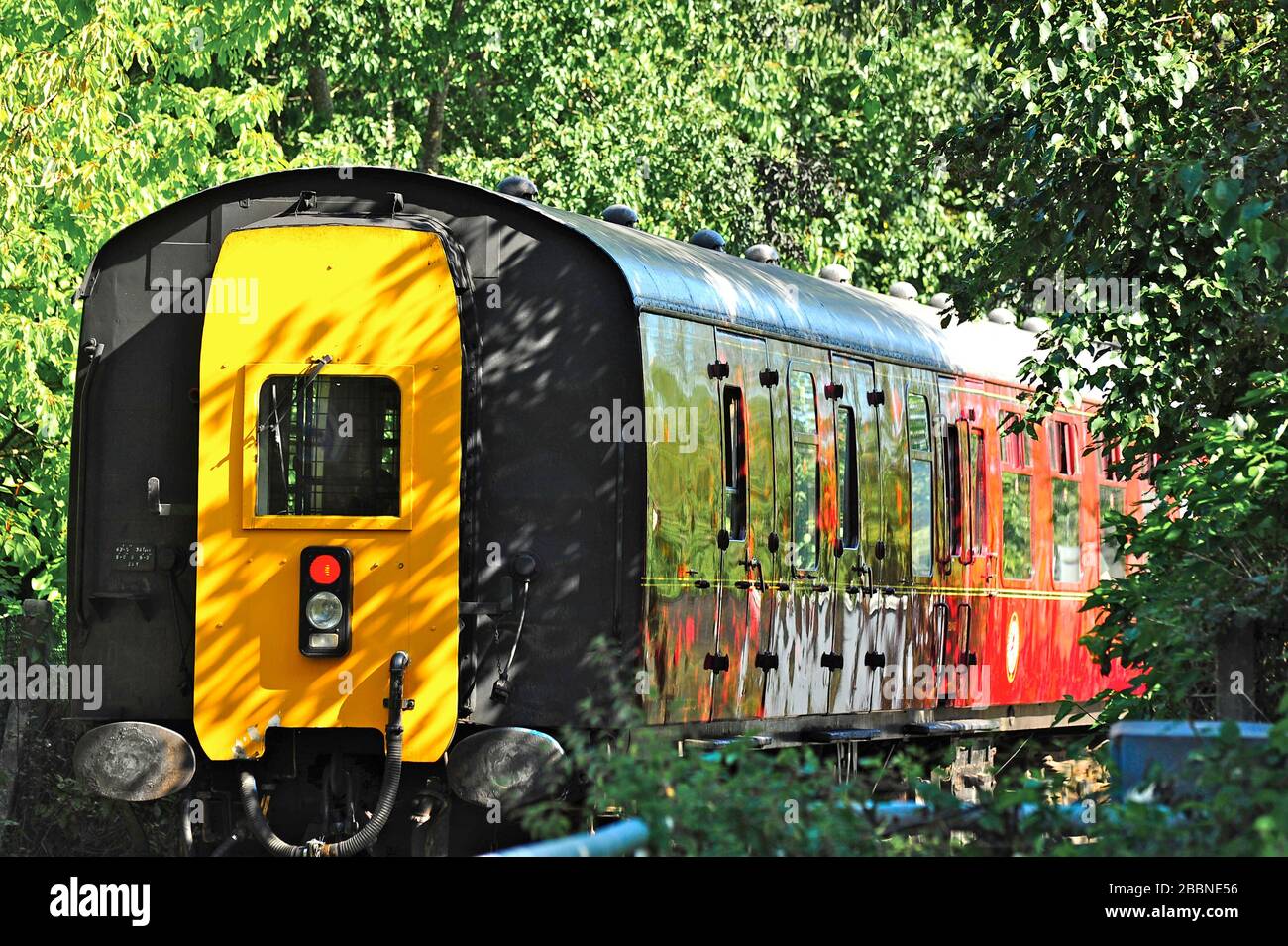 Rear of train carriage disappearing into wooded area on Preston steam
