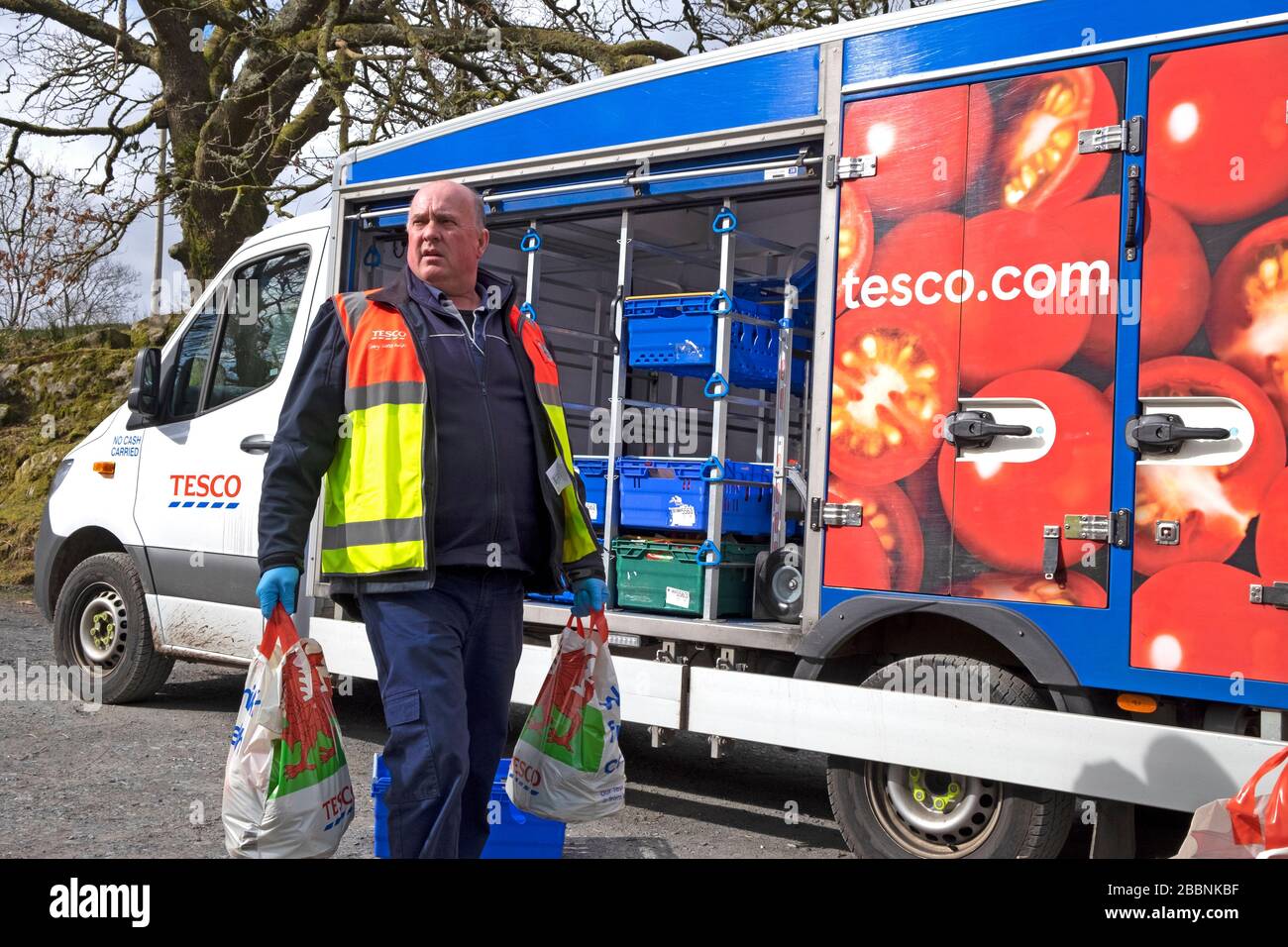 Tesco food van driver delivering groceries in plastic bags to a customer home in rural Wales