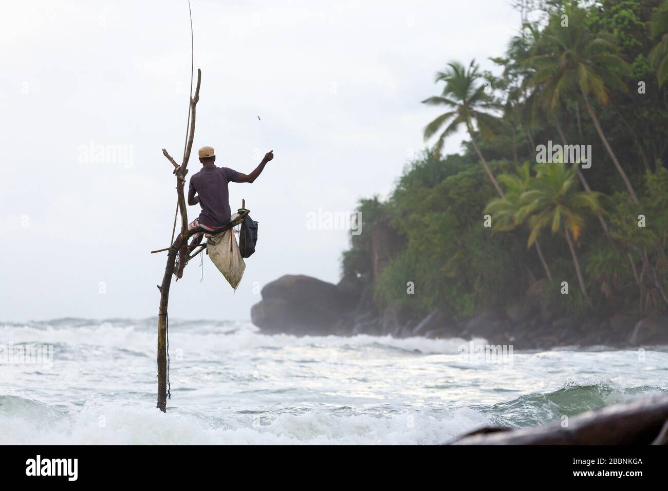 Stilt fisherman casting his line at Mirissa Beach on the south coast of Sri Lanka Stock Photo