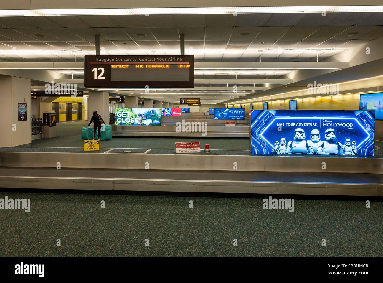 A lone passenger at the baggage carousel with sign for Disney's
