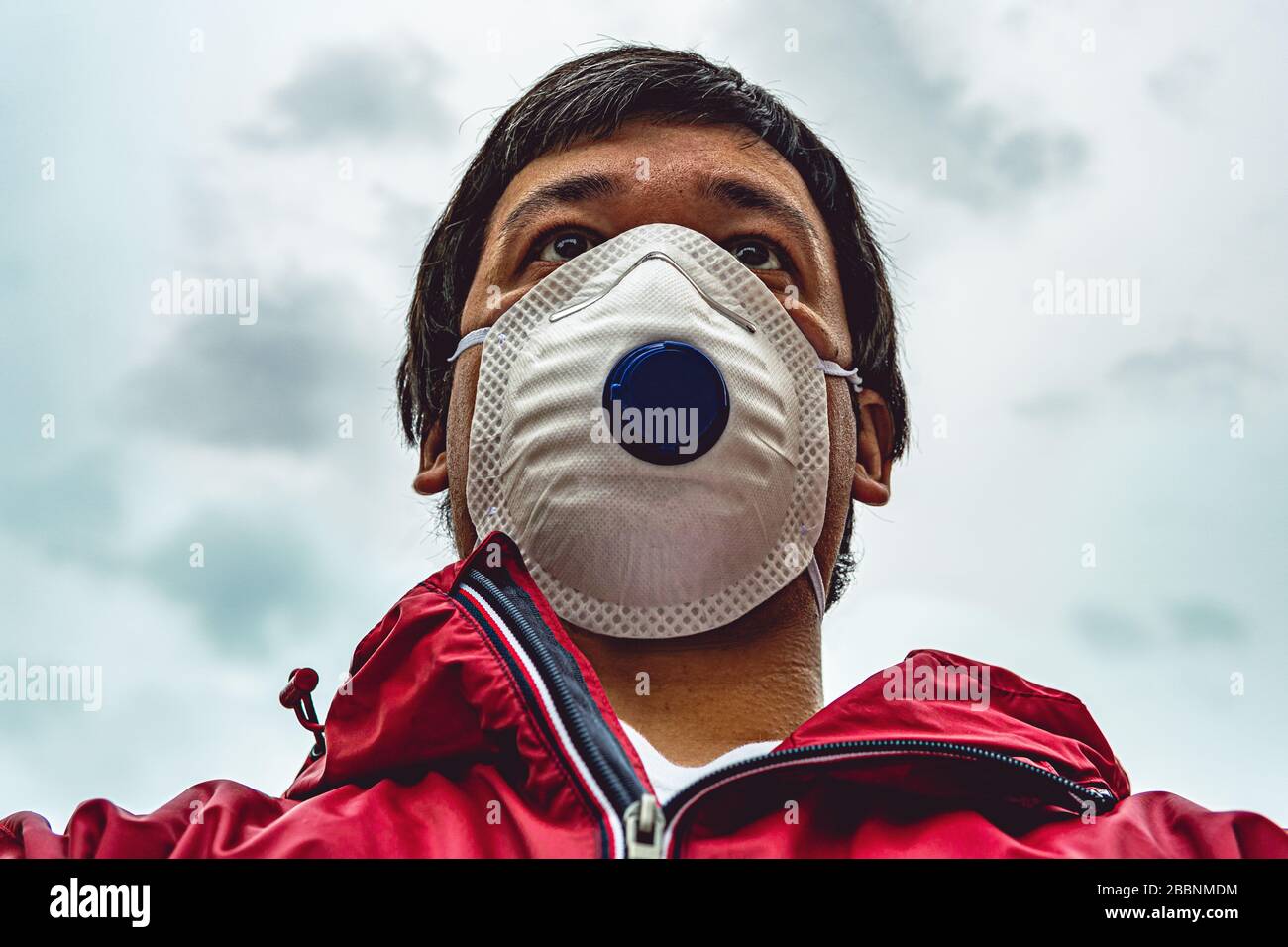 Portrait of man in respirator mask walking on the street, bottom view, violation of quarantine. Theme of corona-virus epidemic. Stock Photo