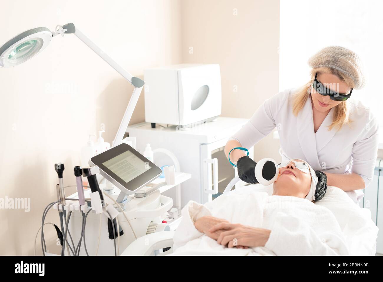 Beauty treatment professional in laser safety goggles cleaning facial