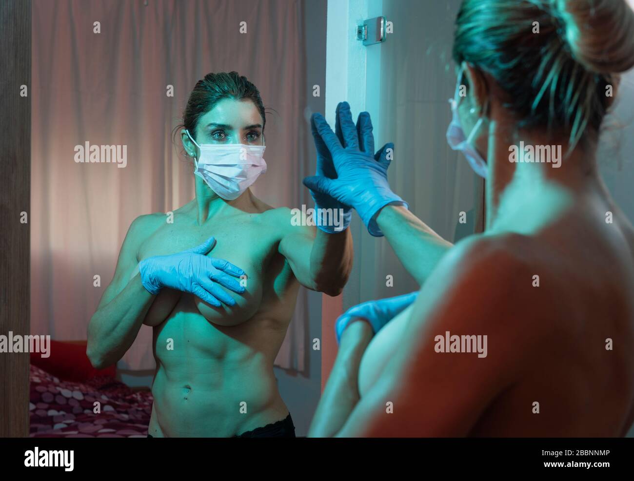 Woman with mask looking at herself in the mirror. Stock Photo