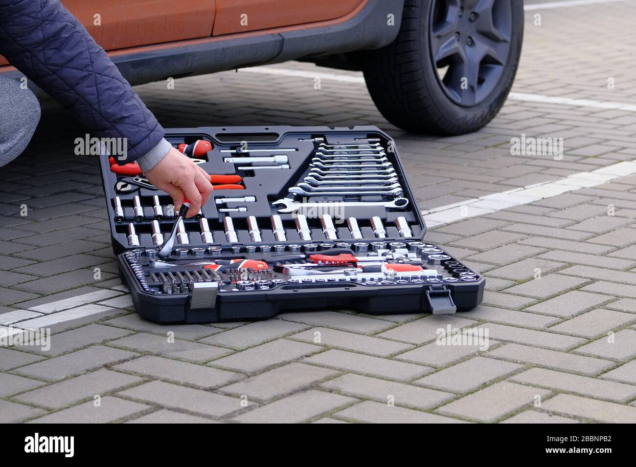 Tool set in box near the orange auto. Сar driver using different repair  tools for repairing a vehicle. Automobile maintenance concept Stock Photo -  Alamy