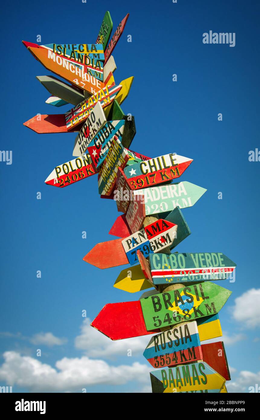 Many colourful wooden direction signs to far locations Stock Photo