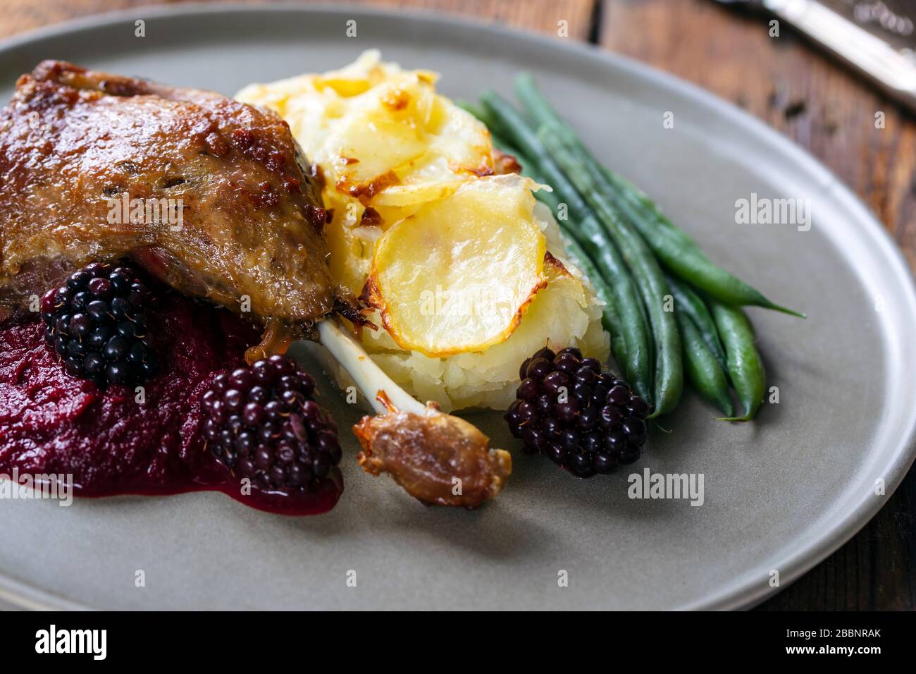 Roast duck leg with beetroot and blackberry puree and dauphinois potatoes Stock Photo