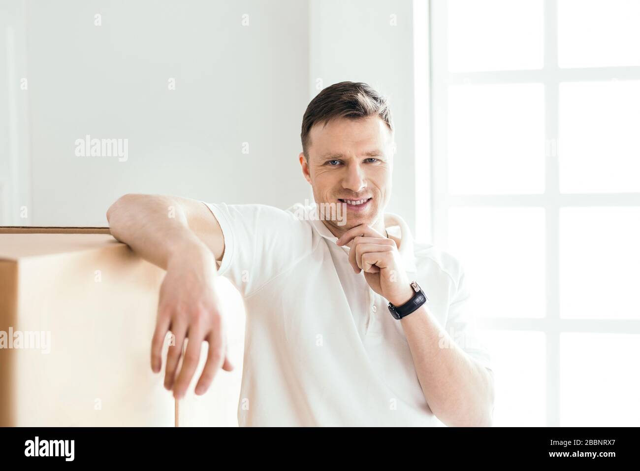 pensive young man standing near cardboard boxes Stock Photo