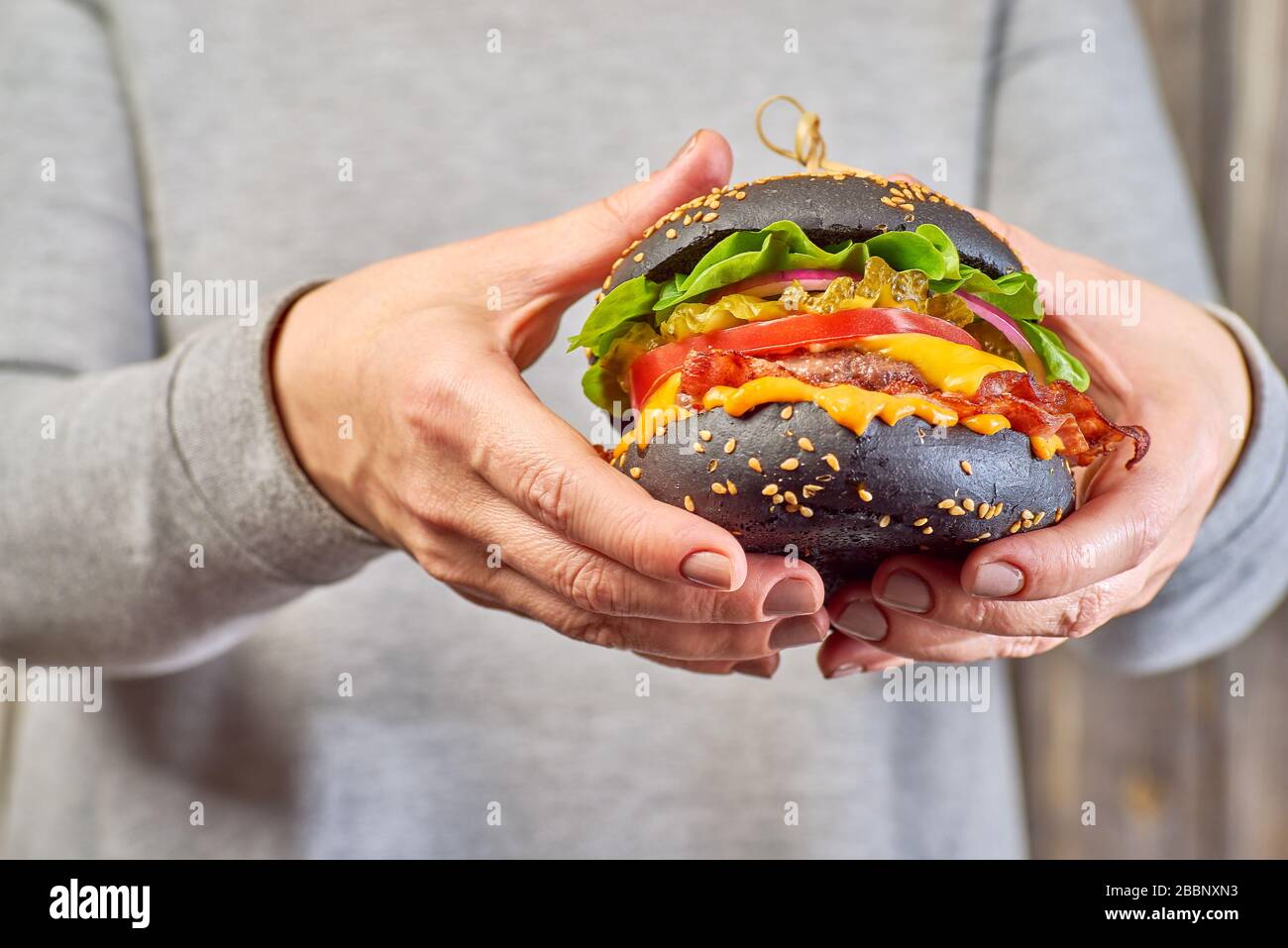 Female hands hold a black hamburger Stock Photo
