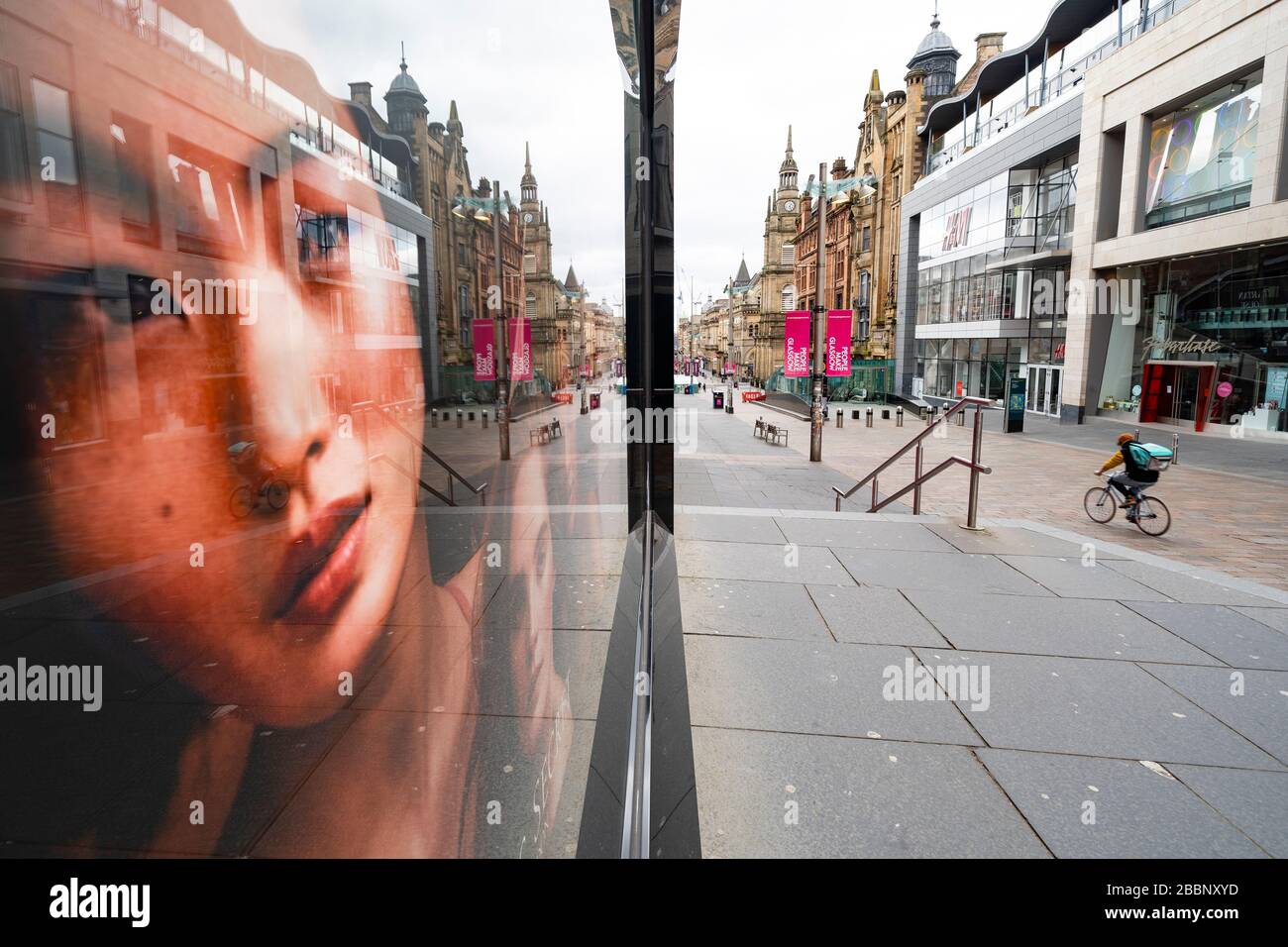 Glasgow, Scotland, UK. 1 April, 2020. Effects of Coronavirus lockdown on streets of Glasgow, Scotland. Photo of model in Victoria's Secret shop looks out on a deserted Buchanan Street with a lone Deliveroo cyclist riding past .Iain Masterton/Alamy Live News Stock Photo