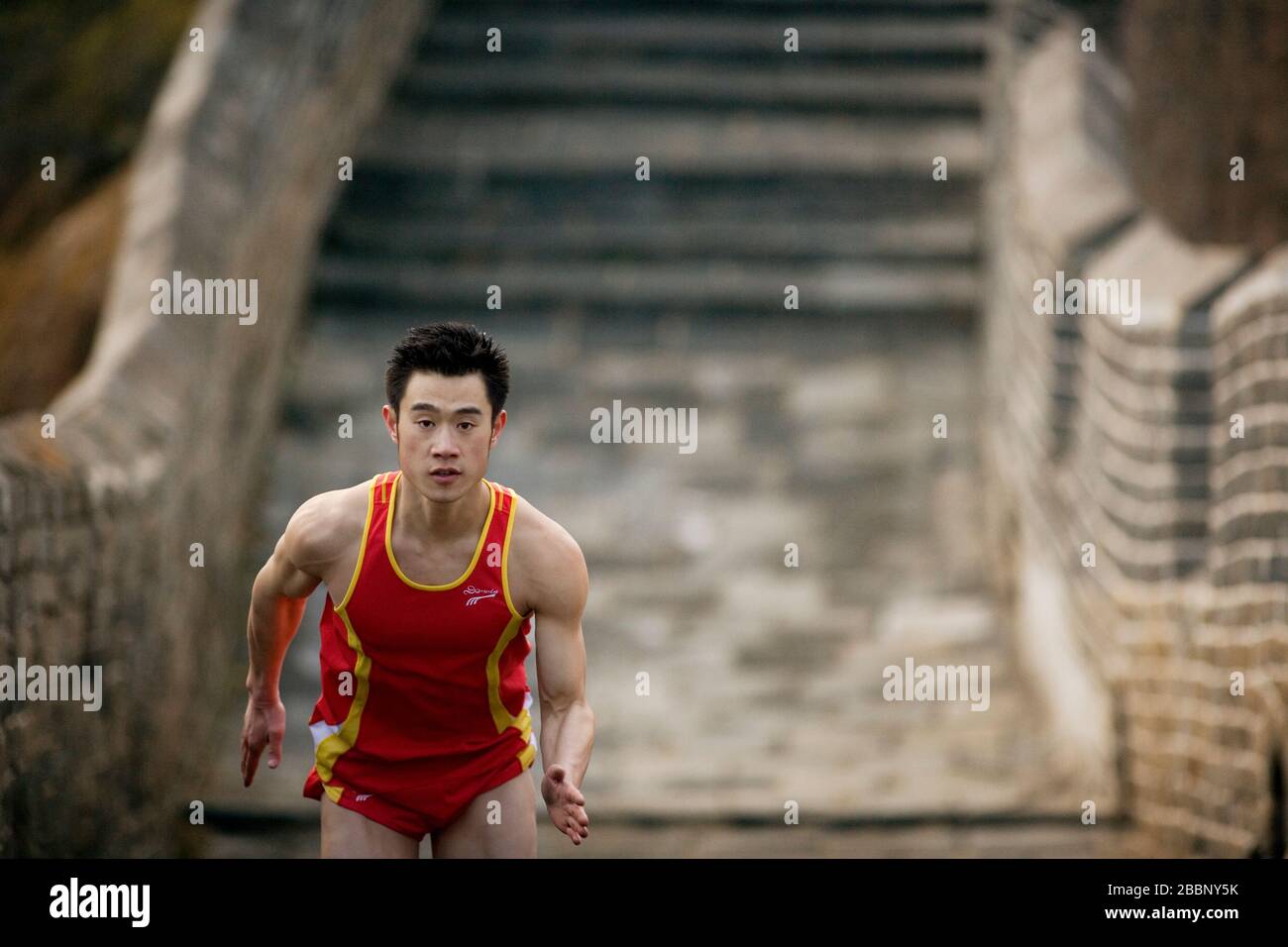 Portrait of a young adult man running along the Great Wall of China. Stock Photo