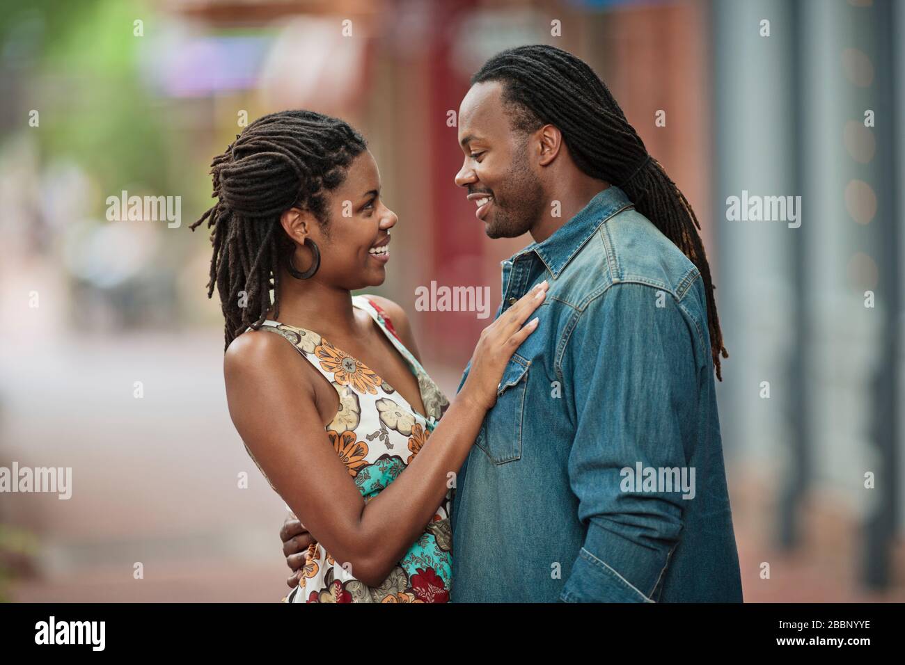 Happy young couple pause on their walk down the street to gaze into each  others eyes Stock Photo - Alamy