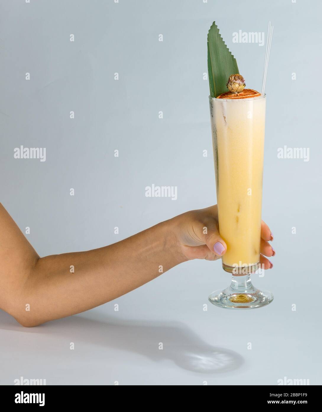 Close up of a woman's hand holding a glass of tropical Pina colada