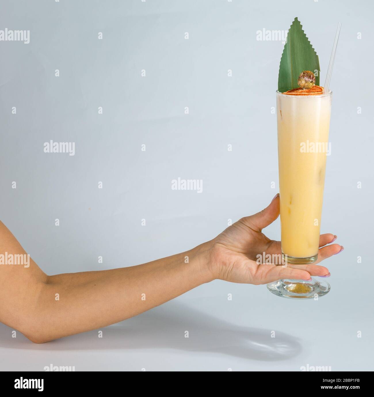 Close up of a woman's hand holding a glass of tropical Pina colada