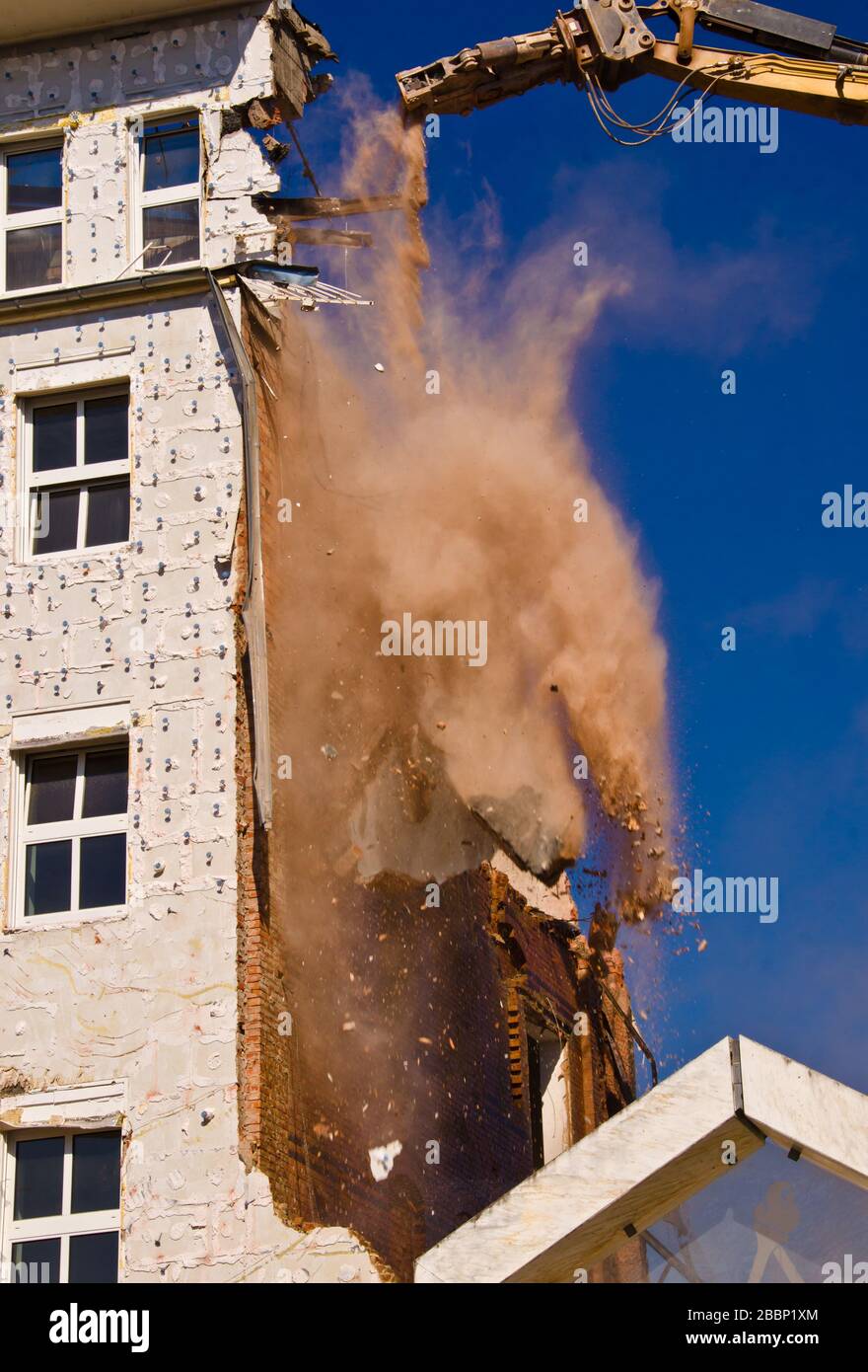 A demolition of a building with a crane with a blue sky background ...