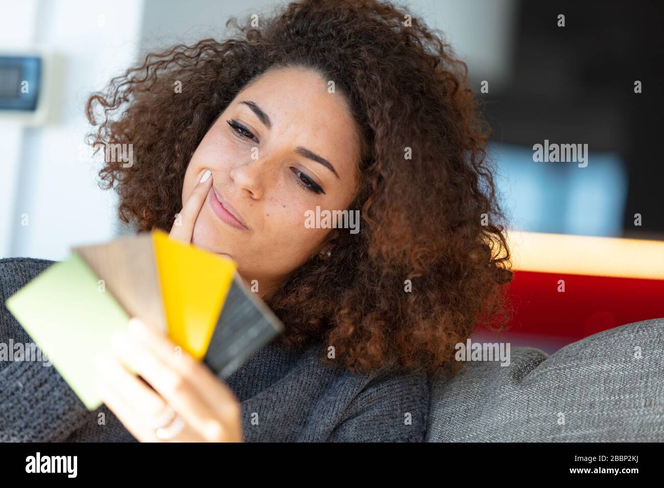 A pretty young woman holding colour samples and deciding on paint colour. Stock Photo