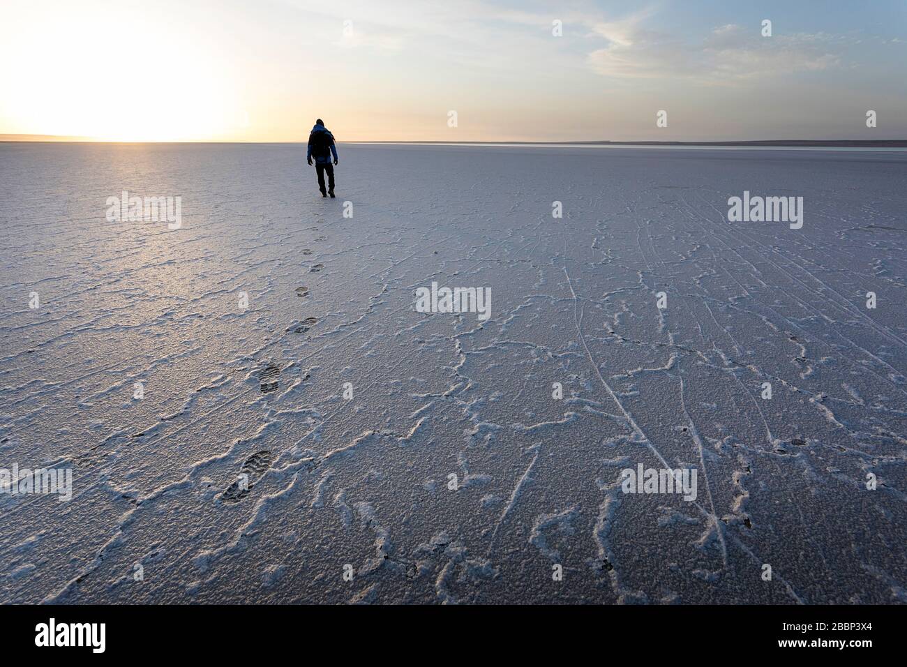 Man walking on salty ground, leaveng foot prints in the dramatic landscape at Tuzbair salt lake, Aktau, Mangystau, Kazakhstan, Stock Photo