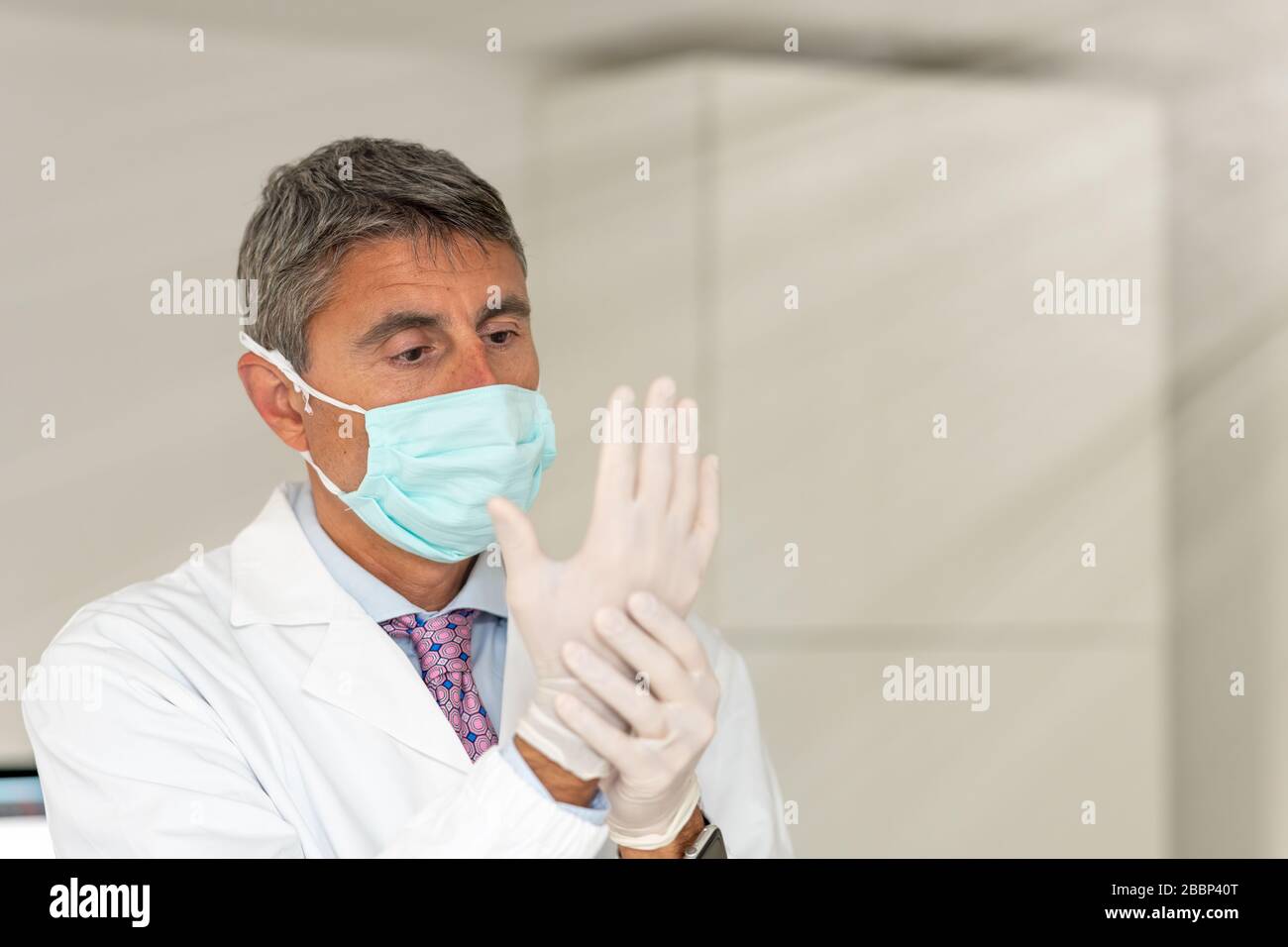 Confident doctor wearing mask and gloves at the medical studio in coronavirus times. Stock Photo