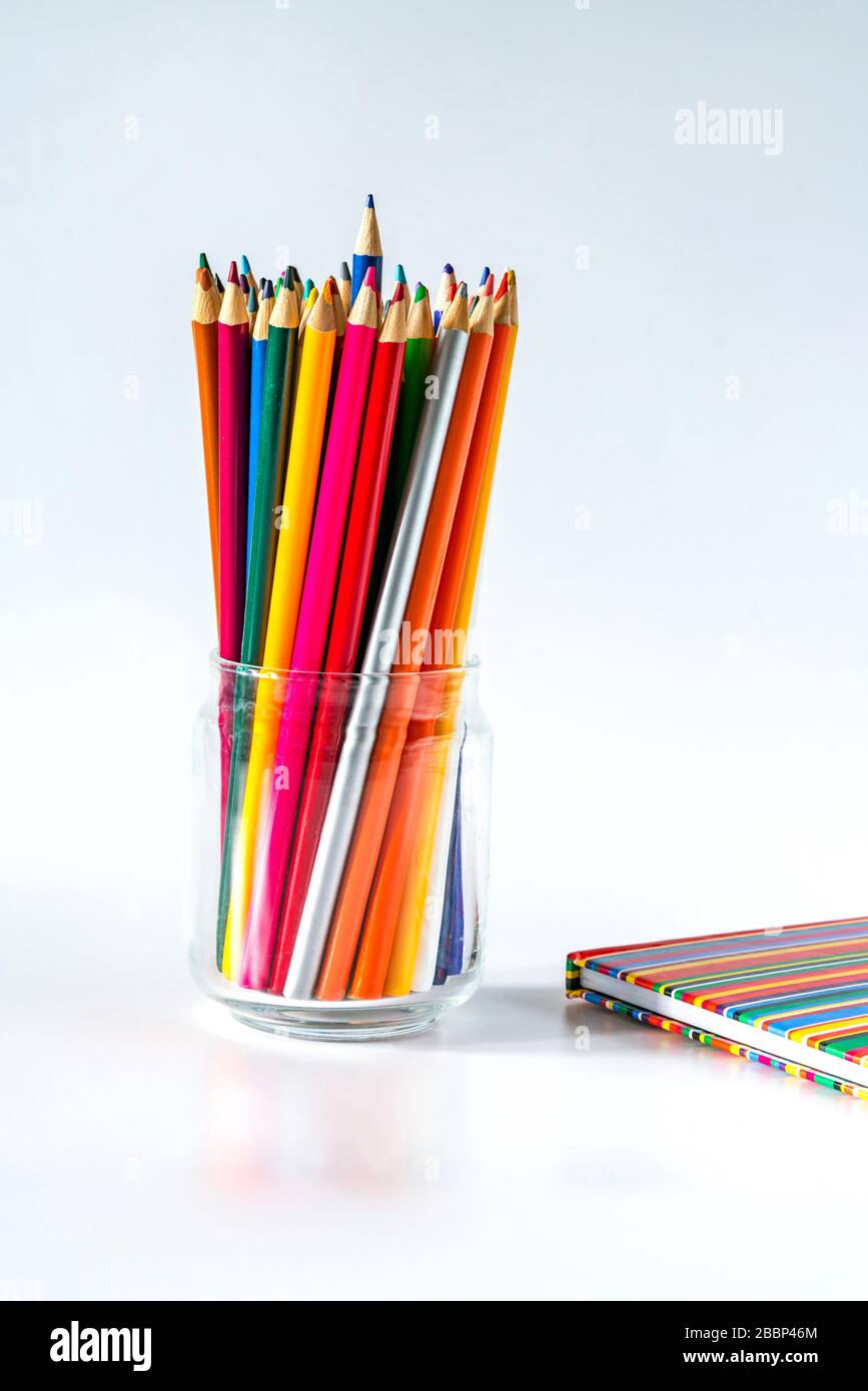 Colorful pencils and a notebook on white background Stock Photo
