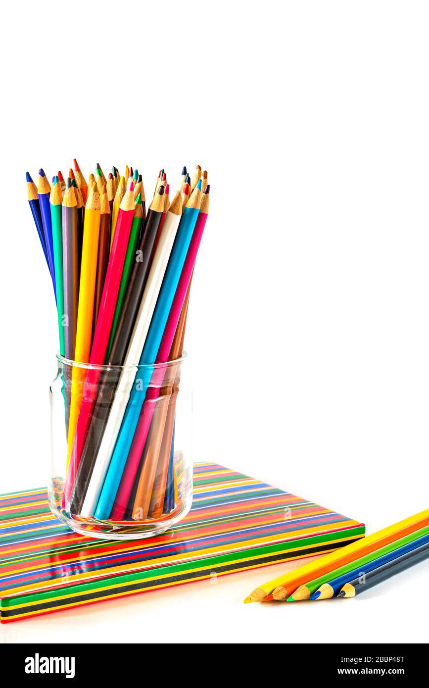 Colorful pencils and a notebook on white background Stock Photo
