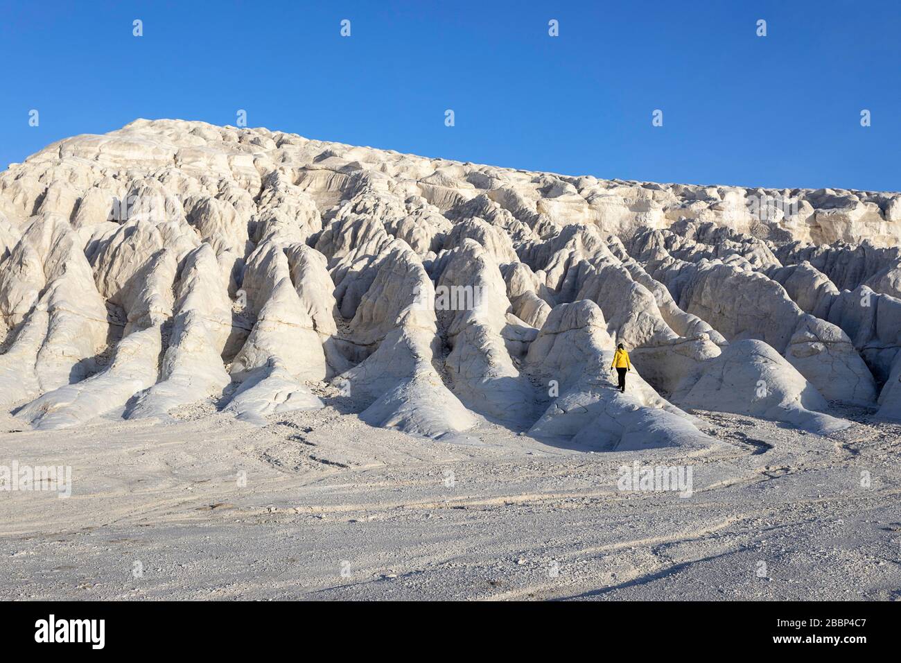 Woman in yellow jacket standing on white rock formations in the