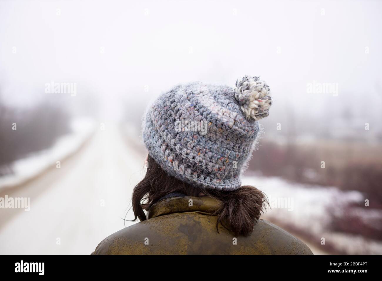 A lady walks alone on a gravel road during the emergency regulations regarding the coronavirus / COVID-19, on a foggy cold spring day. Stock Photo