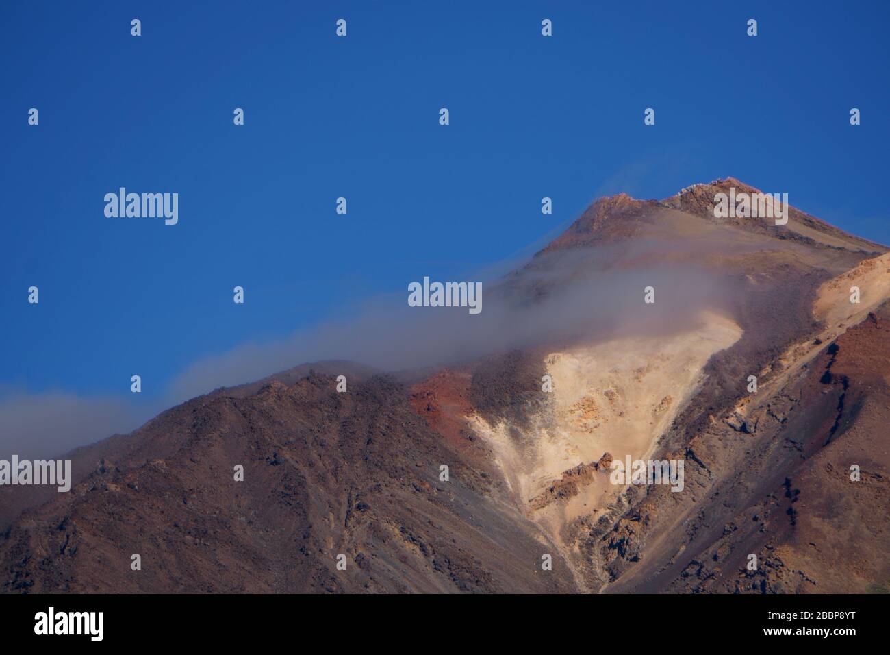 View of volcanic mountain against blue sky Stock Photo