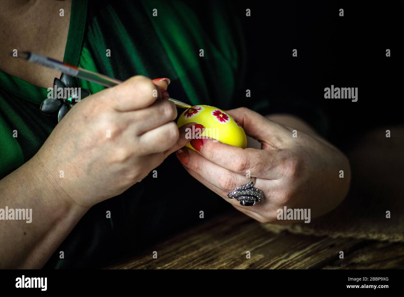 Holidays, traditional concept - close up of woman hands coloring Easter eggs with brush ...