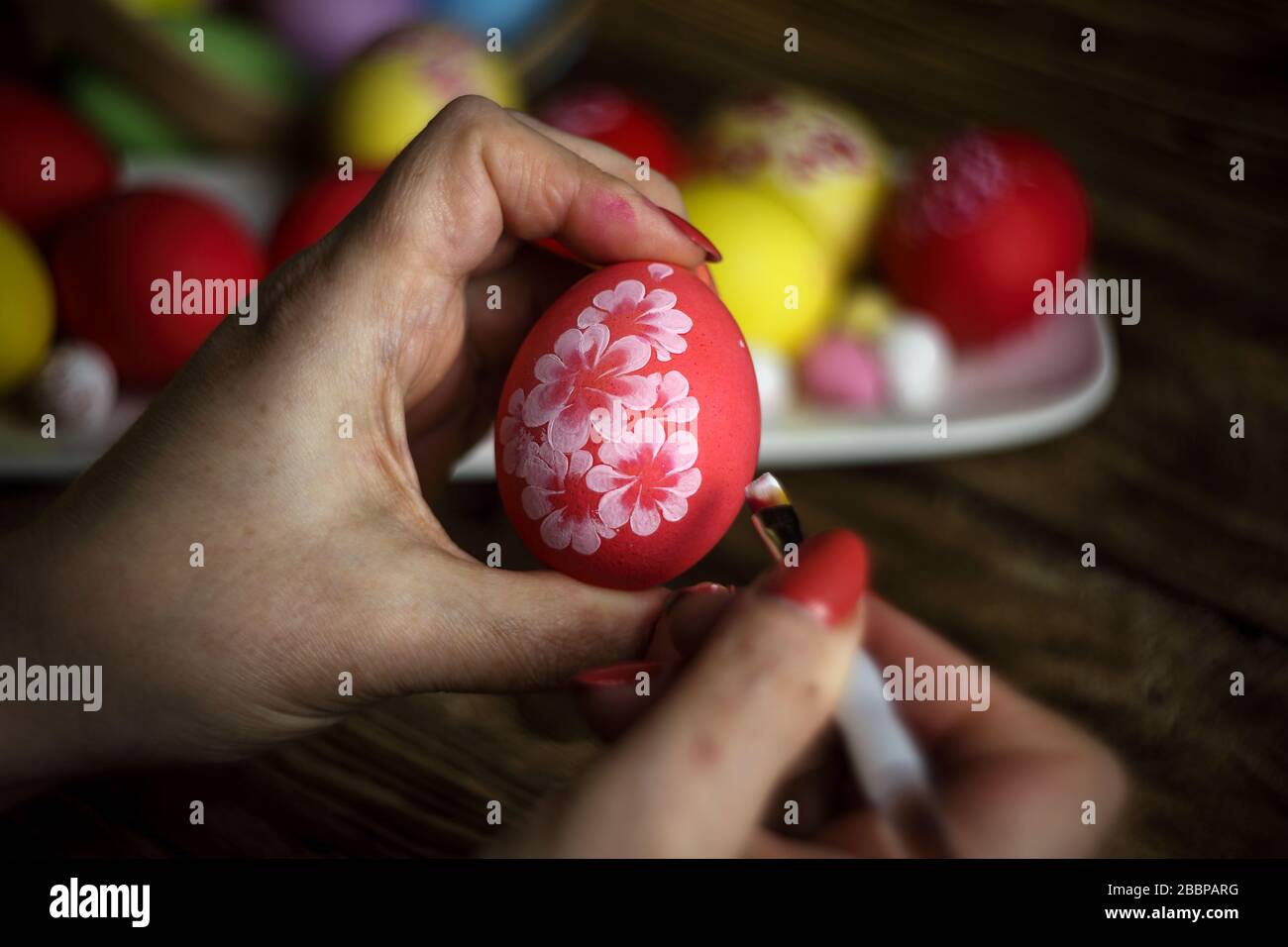 Close-up of woman's hands painting an easter egg. Painting Easter eggs. Painting eggs for easter holiday celebration. Happy easter. Low Key. Stock Photo