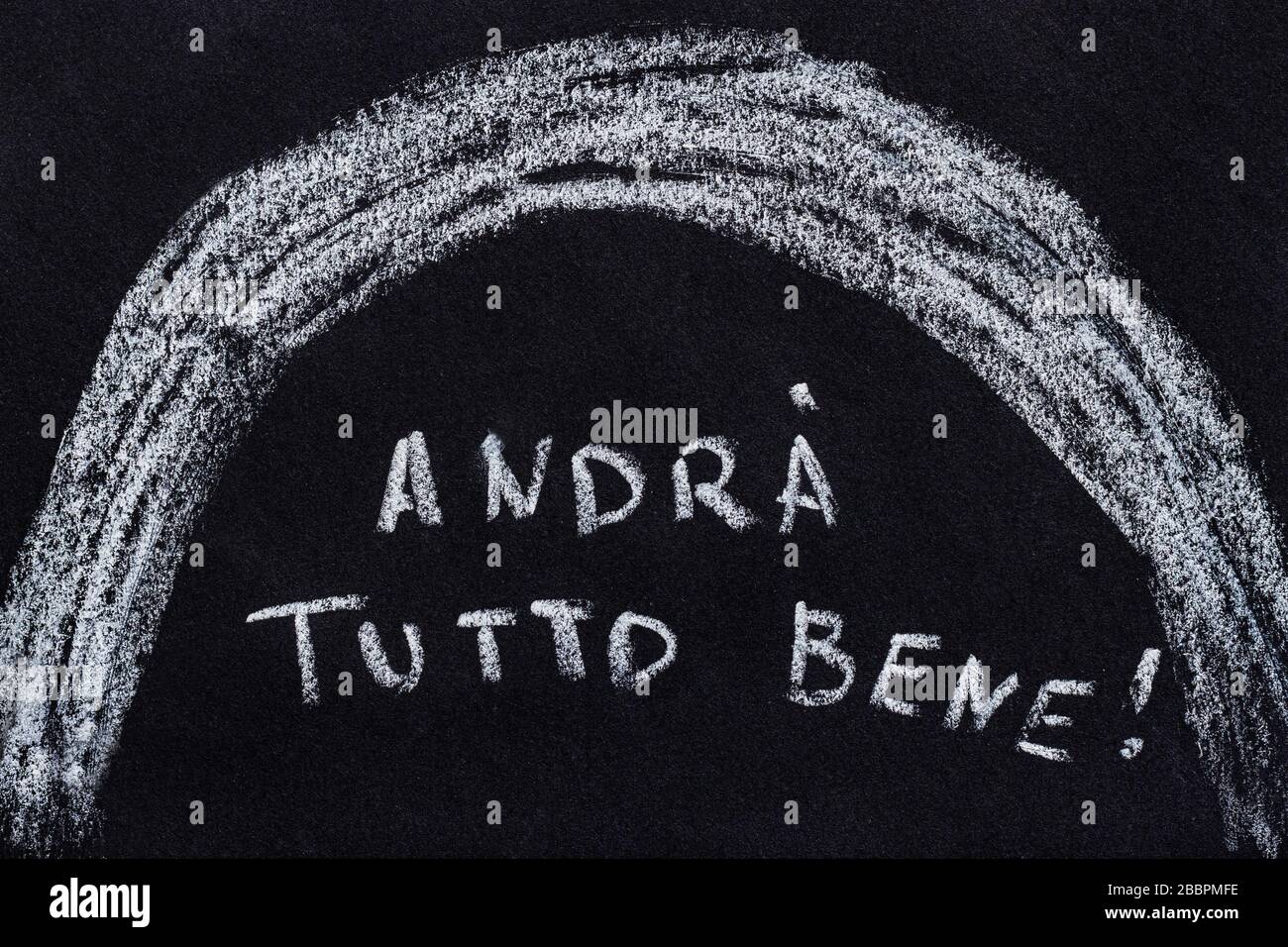 Drawing with chalk on a black blackboard, handwritten italian text andrá tutto bene which translate as everything will be fine Stock Photo
