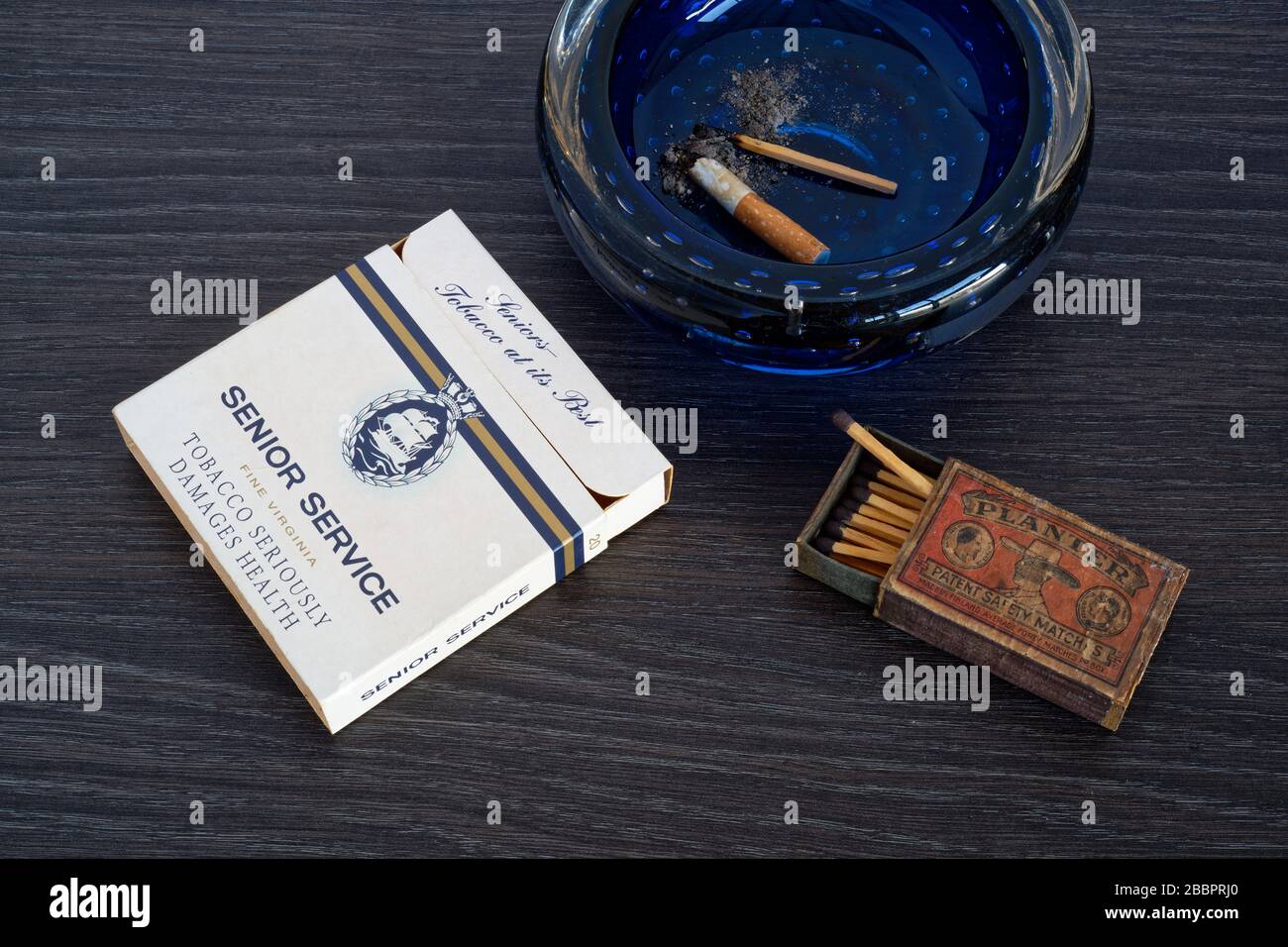 A packet of Senior Service cigarettes with matches and an ashtray. Stock Photo