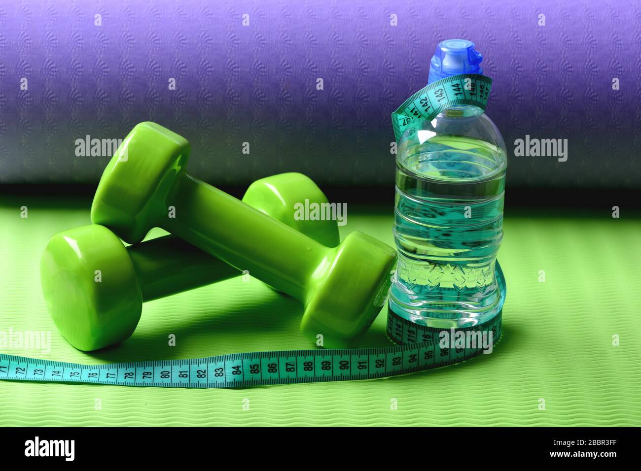 https://c8.alamy.com/comp/2BBR3FF/shaping-and-fitness-equipment-barbells-near-cyan-measuring-tape-roll-and-water-bottle-sports-and-healthy-lifestyle-concept-dumbbells-made-of-green-plastic-on-green-and-purple-texture-background-2BBR3FF.jpg