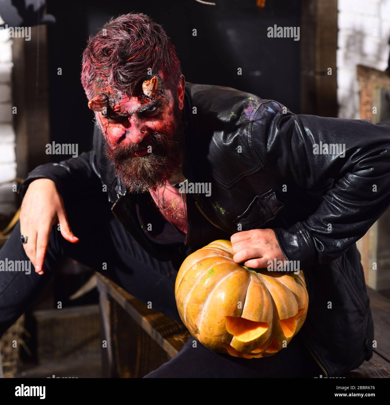 Man wearing scary makeup with Halloween pumpkins and bats decor on 