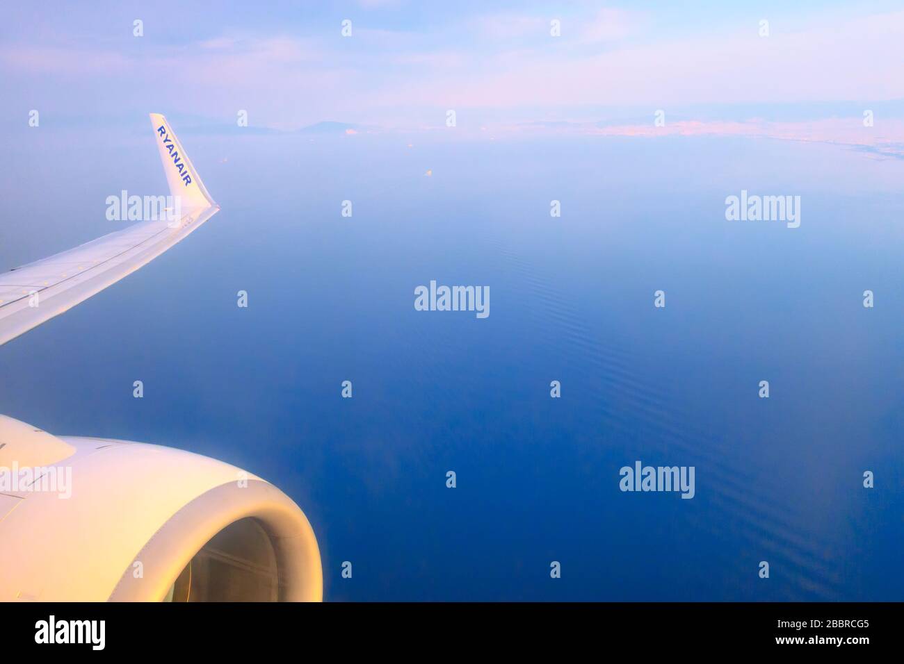 Athens, Greece - April 22, 2019: Low-cost airline Ryanair logo on airplane's wing and turbine, blue sea and Athens coastline Stock Photo