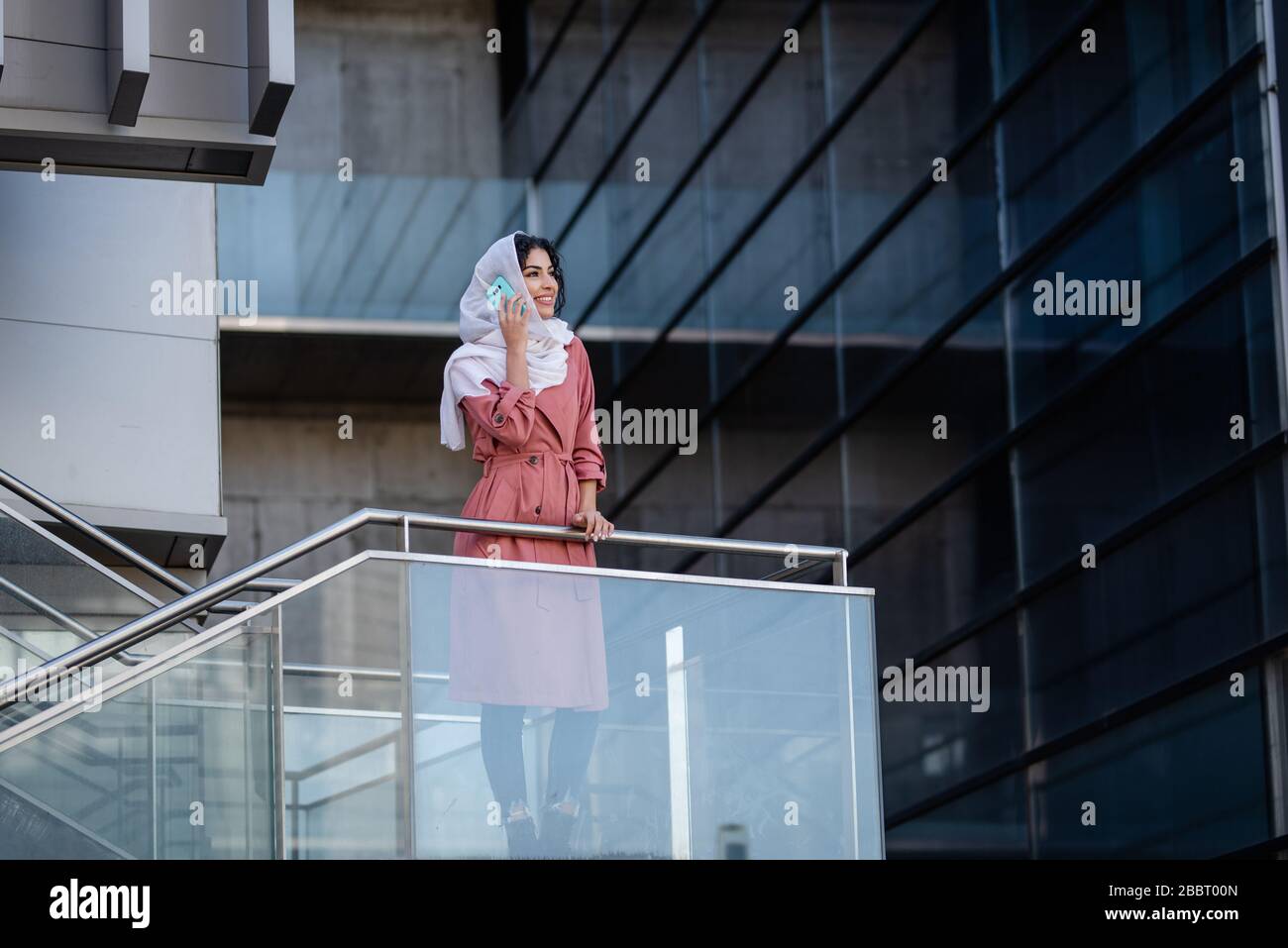 Mixed race young woman wearing hijab on a built structure  Stock Photo