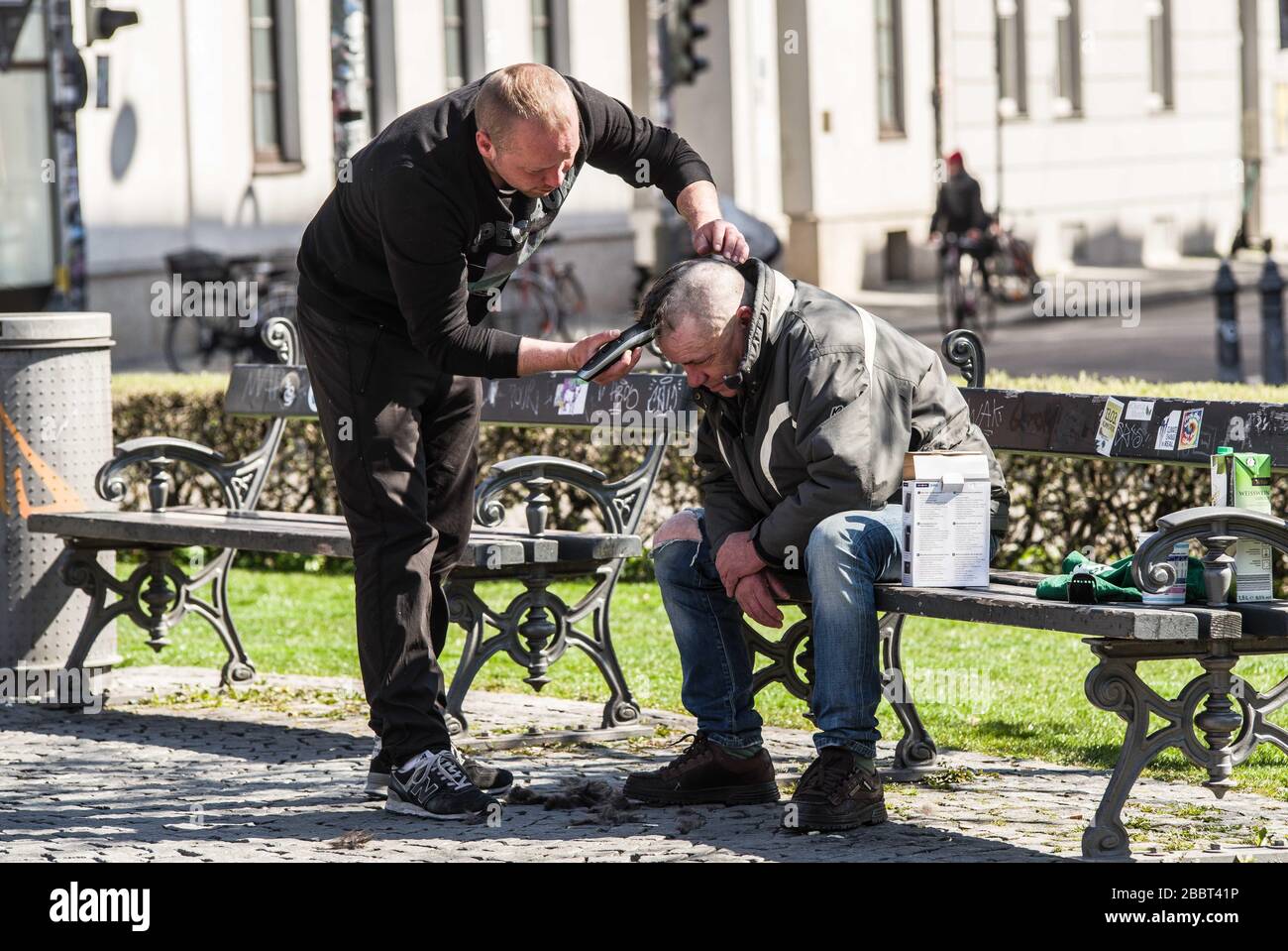 Munich, Bavaria, Germany. 1st Apr, 2020. A man at Munich's Gaertnerplatz gives another a haircut. It is unclear if this is allowed under the Kontaktsperre rules. Despite being cautiously optimistic regarding the efforts to flatten the curve, Parts of Germany, such as Bavaria, have announced extensions to the daily life restrictions at least until April and with certain portions extending beyond. Credit: Sachelle Babbar/ZUMA Wire/Alamy Live News Stock Photo