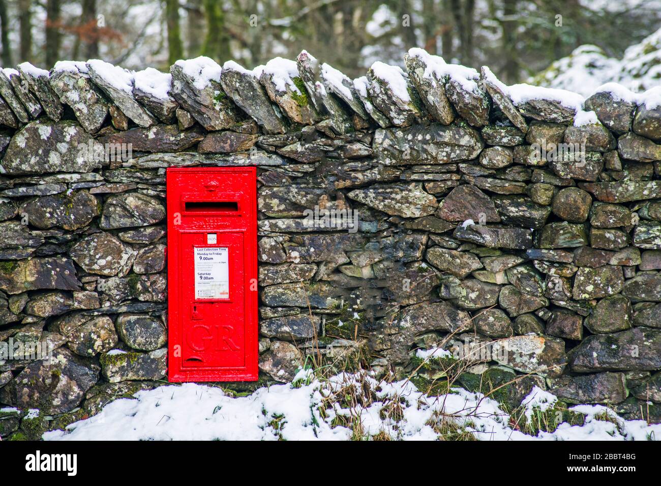 A bright ref GR letterbox mounted into a stone wall near Loughrigg Tarn in the English Lake District National Park Stock Photo