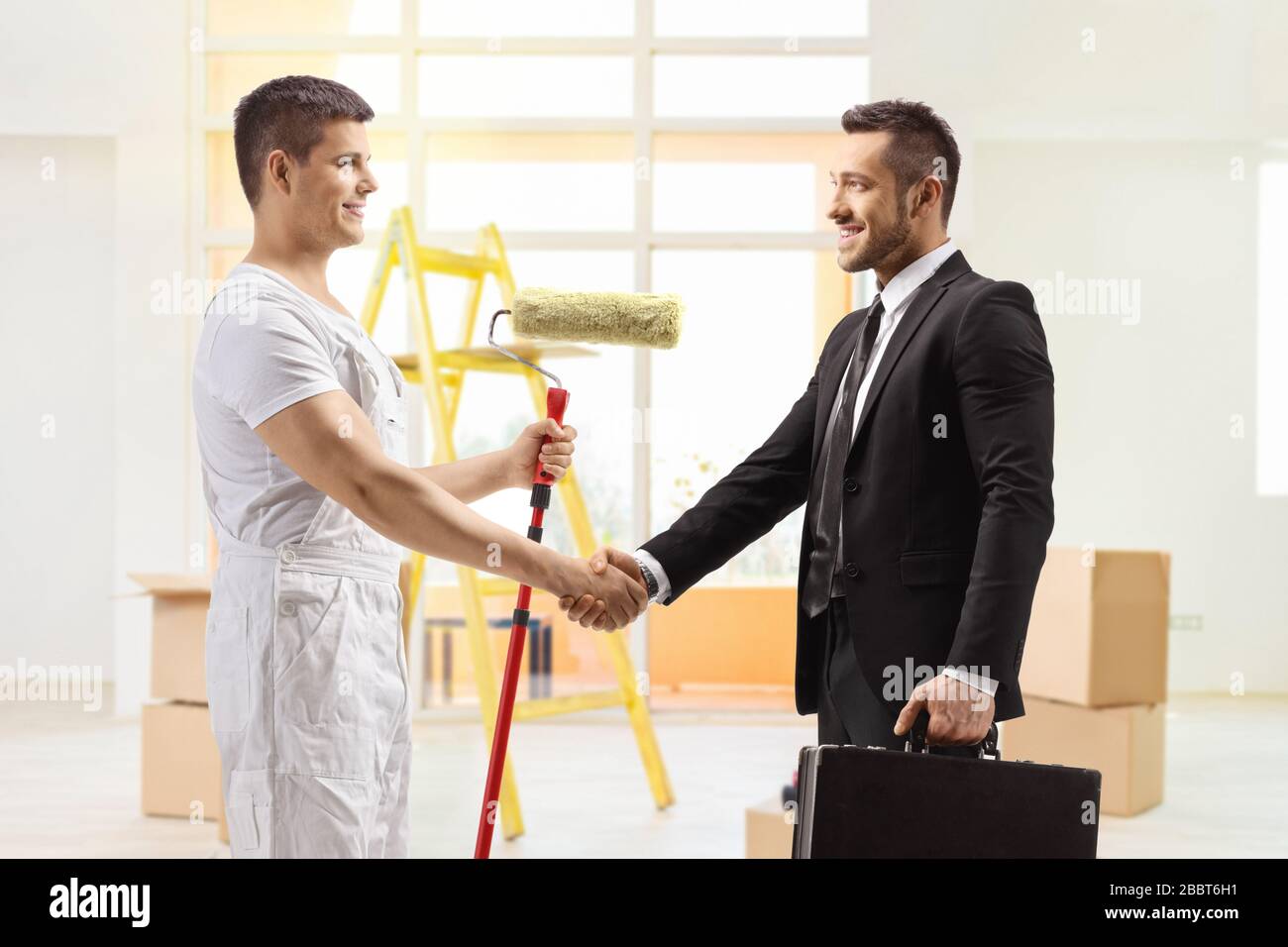 Decorator with a paint roller shaking hands with a businessman Stock Photo
