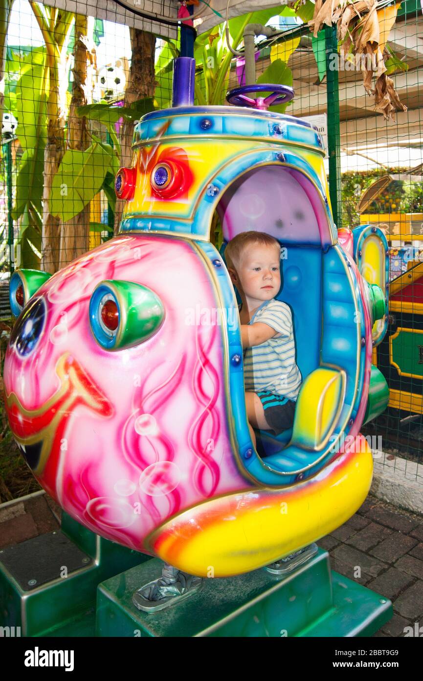A three-year-old little fair-haired boy rides in a children's rocket in ...