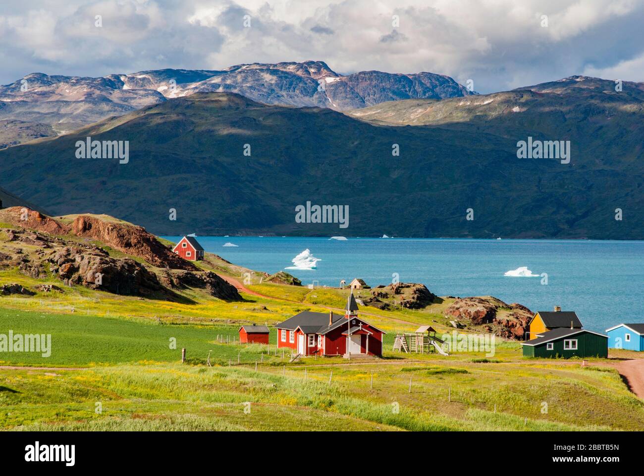 View of Narsarsuaq and fjord from above hill. Summer in Greenland. In the background mountains and blue sky with some clouds. Stock Photo