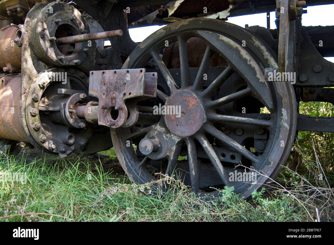 Old dysfunctional railway steam locomotive which is overgrown with weeds. Stock Photo