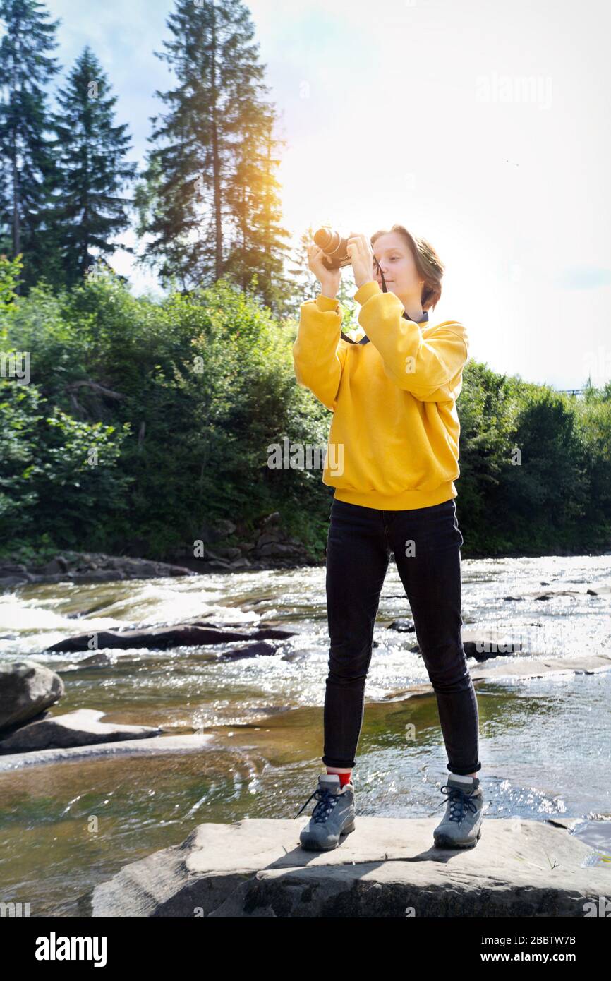 tourist girl with camera standing on the bank of a mountain river Stock ...