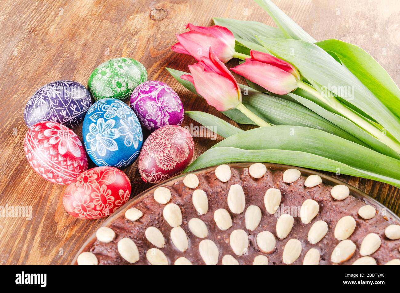 colorful easter eggs, easter cake and tulips on wooden table Stock Photo