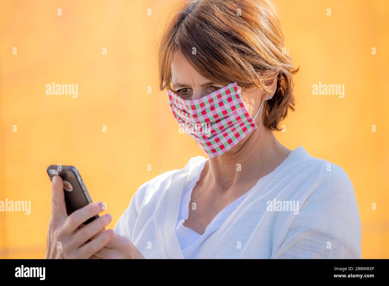 Woman wears a breathing mask, self-sewn, made of cotton, talks on a mobile phone, effects of the corona crisis in Germany Stock Photo