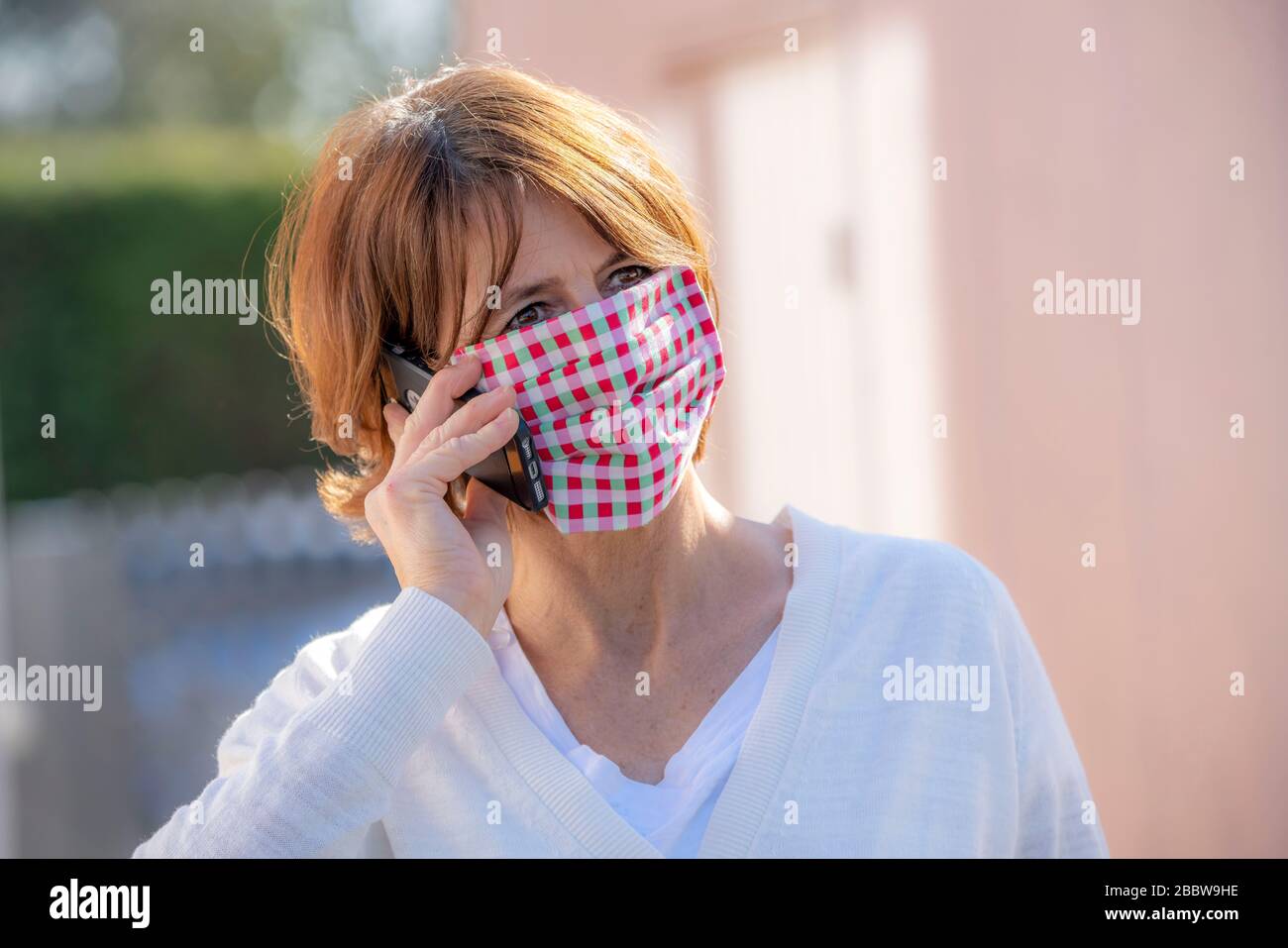 Woman wears a breathing mask, self-sewn, made of cotton, talks on a mobile phone, effects of the corona crisis in Germany Stock Photo