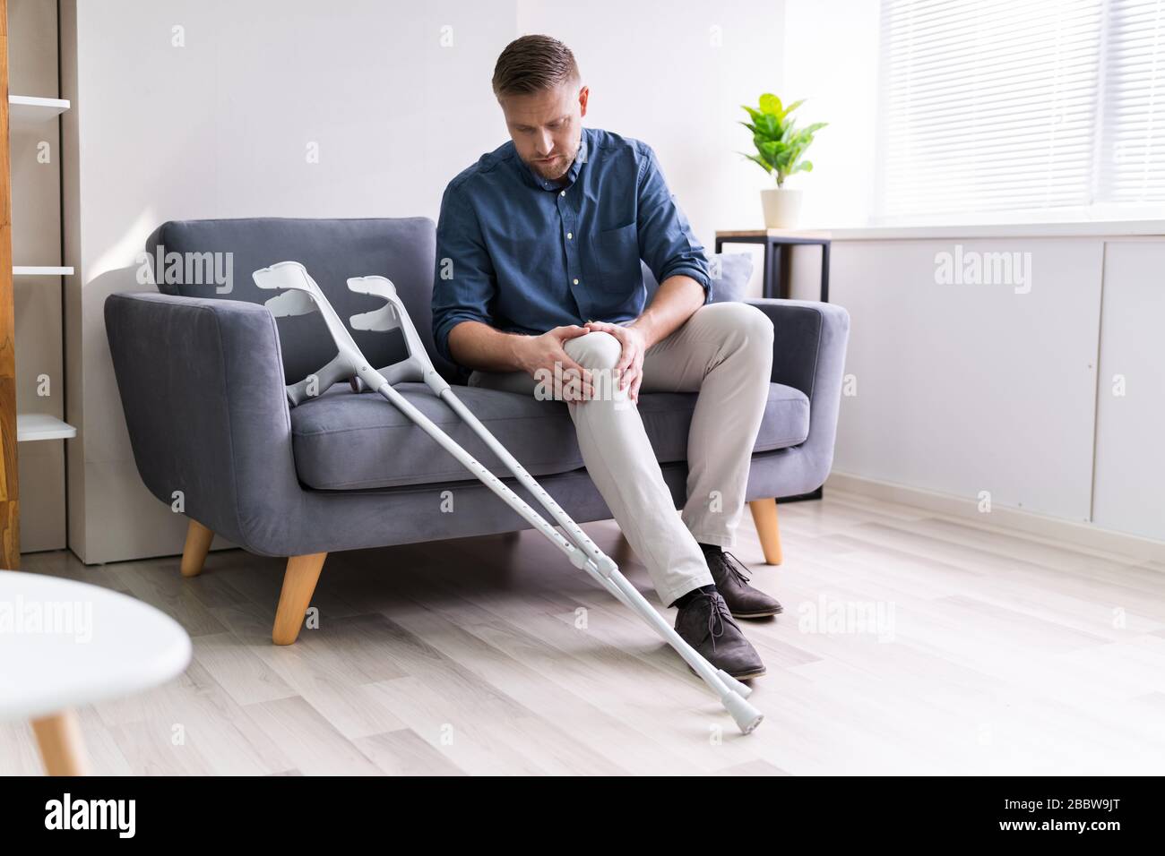 Man Suffering From Knee Pain Sitting On Sofa Stock Photo Alamy